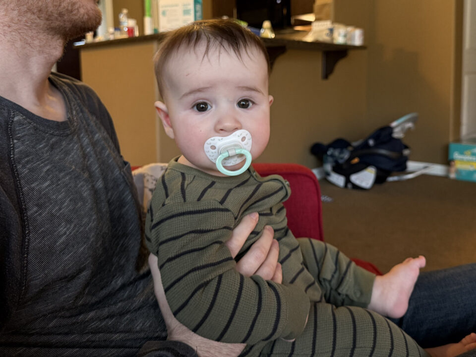 Jack Henry with a binky, sitting on Jon's lap