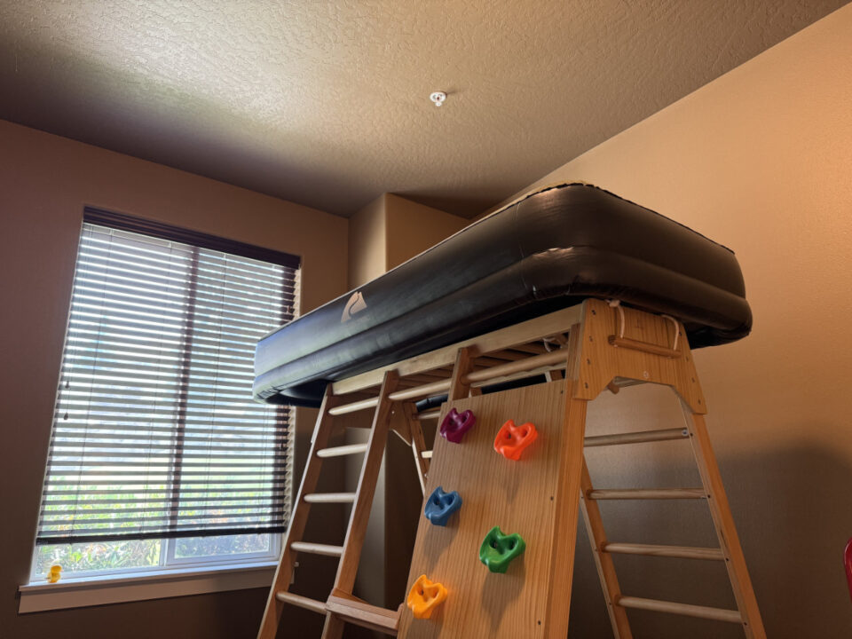 An inflatable bed stored atop a jungle gym