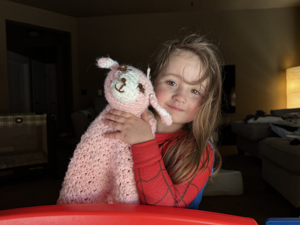 Olivia wearing a her Spidey jammies and holding her pink wooly lamb plushie