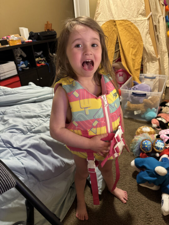 Olivia wearing a bright life jacket in her bedroom