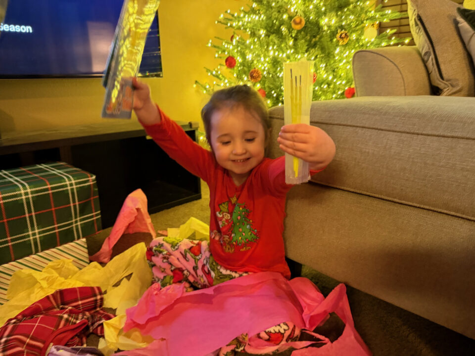 Olivia in Grinch jammies holding up presents